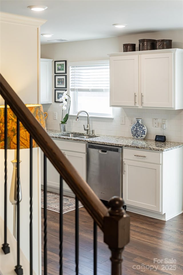 kitchen with dark hardwood / wood-style floors, stainless steel dishwasher, sink, white cabinetry, and light stone countertops