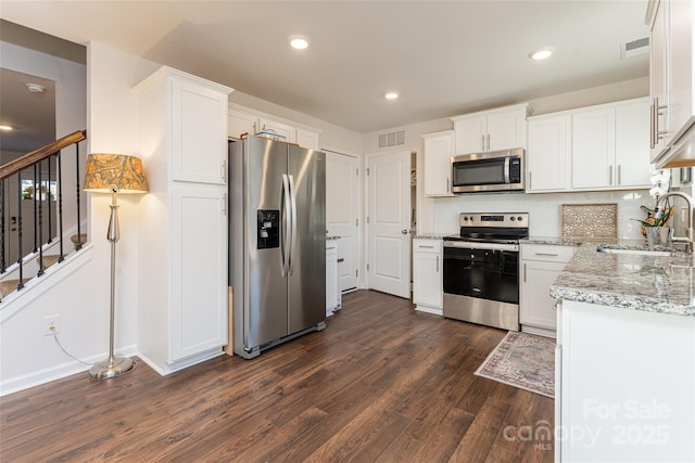 kitchen with light stone countertops, white cabinetry, stainless steel appliances, tasteful backsplash, and sink