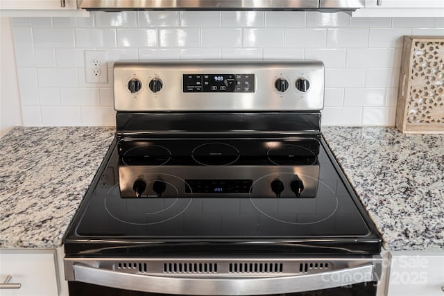 interior details featuring light stone counters, backsplash, and electric range