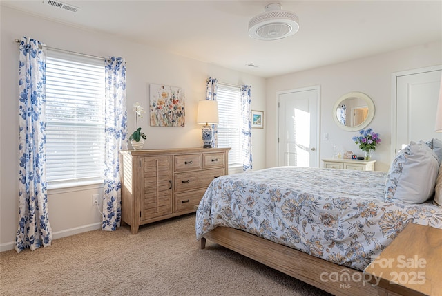 bedroom featuring light colored carpet and multiple windows