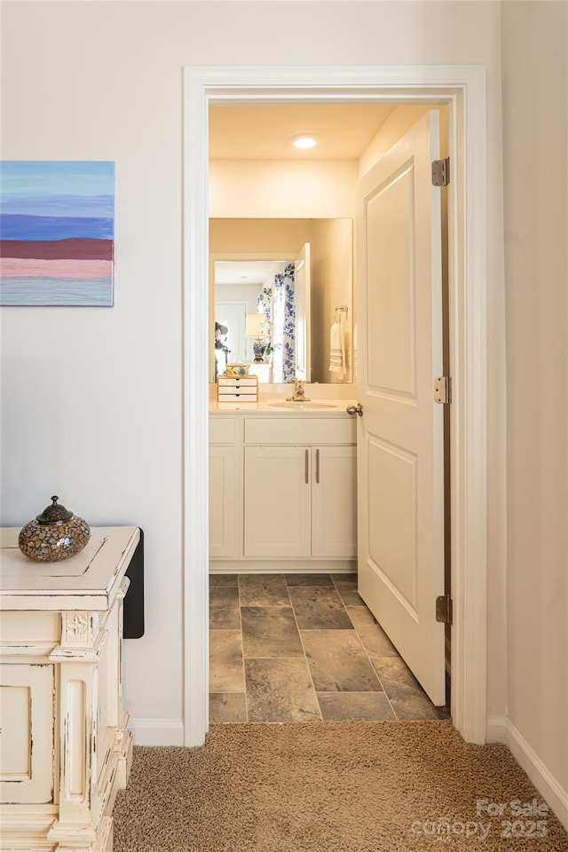 corridor featuring sink and dark carpet