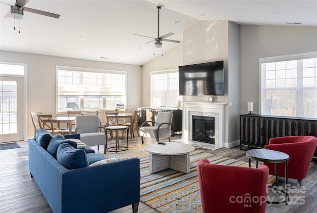 living room with ceiling fan, plenty of natural light, a premium fireplace, and hardwood / wood-style floors