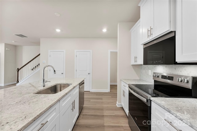 kitchen featuring sink, white cabinets, light stone countertops, light hardwood / wood-style floors, and stainless steel appliances