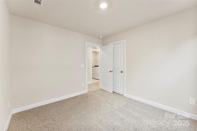 spare room featuring light colored carpet and washer / dryer