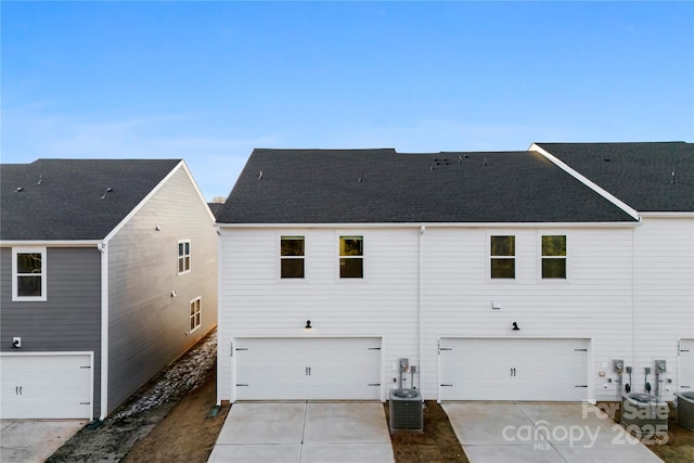 back of house with a garage and central air condition unit