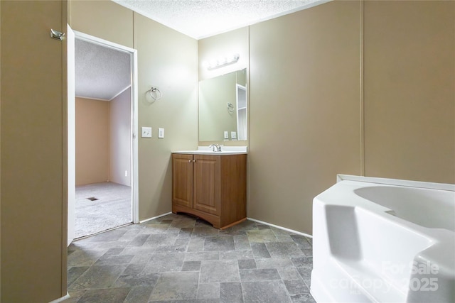 bathroom with a textured ceiling, vanity, and a tub