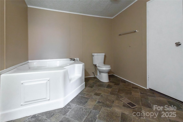 bathroom featuring a washtub, a textured ceiling, and toilet