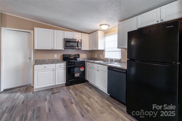 kitchen with sink, black appliances, white cabinets, light hardwood / wood-style floors, and lofted ceiling