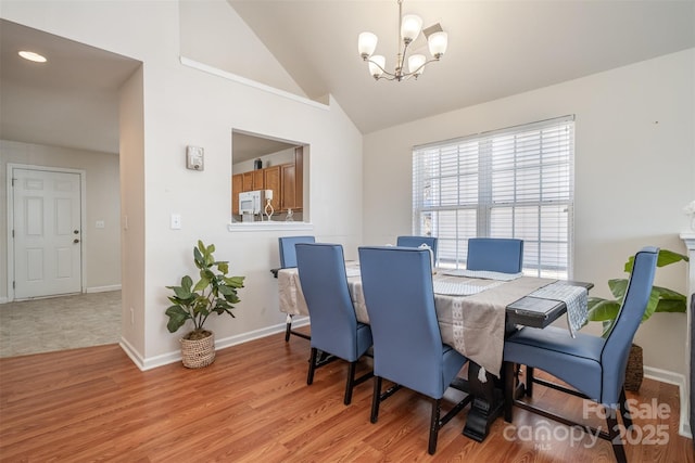 dining area featuring a chandelier, light hardwood / wood-style flooring, and lofted ceiling