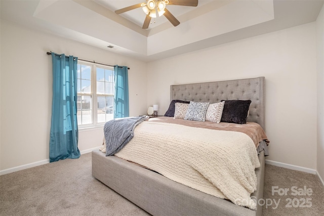 carpeted bedroom with ceiling fan and a raised ceiling