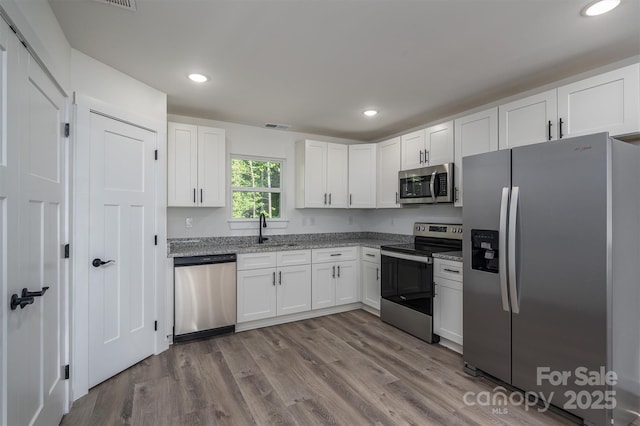 kitchen with light stone counters, sink, white cabinets, and stainless steel appliances