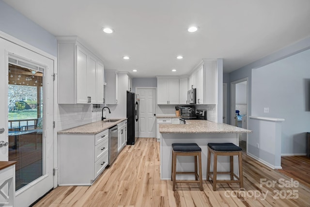 kitchen with a breakfast bar area, backsplash, white cabinetry, and stainless steel appliances