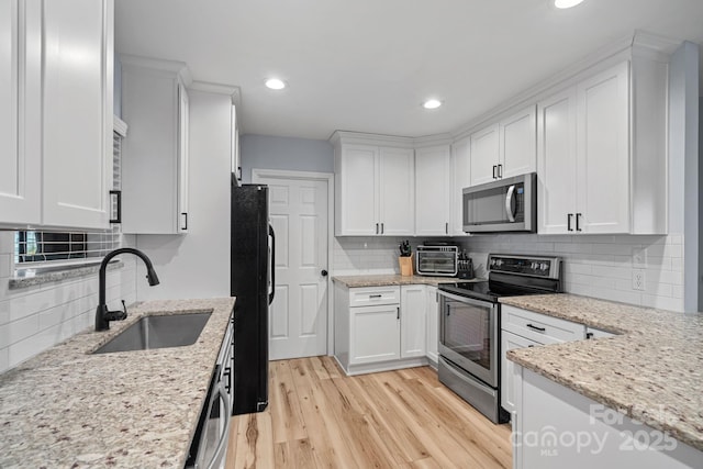 kitchen featuring white cabinetry, sink, light stone countertops, tasteful backsplash, and appliances with stainless steel finishes