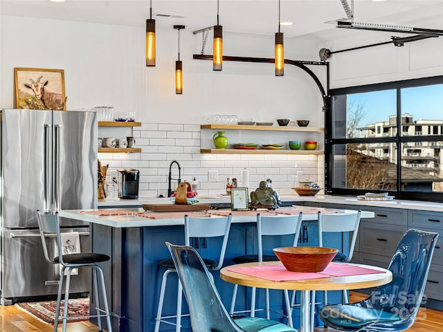 kitchen with decorative light fixtures, stainless steel fridge, a kitchen breakfast bar, and decorative backsplash