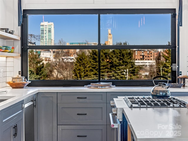 kitchen with decorative backsplash, stainless steel gas stove, and gray cabinetry