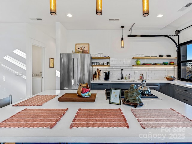 kitchen with pendant lighting, sink, and stainless steel refrigerator