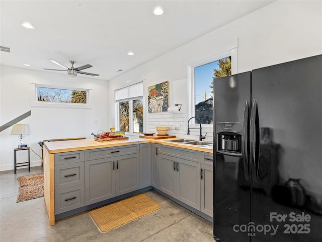 kitchen featuring black fridge with ice dispenser, ceiling fan, gray cabinetry, and sink