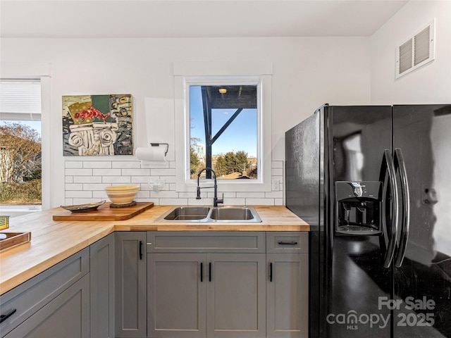 kitchen featuring wood counters, gray cabinets, black refrigerator with ice dispenser, and sink