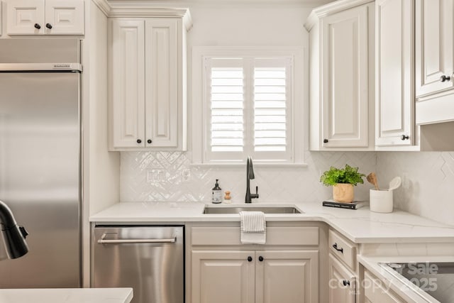 kitchen with stainless steel appliances, white cabinets, backsplash, and sink