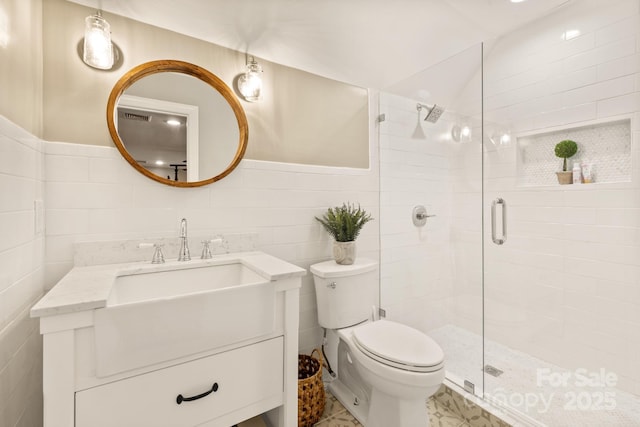 bathroom featuring a shower with door, tile walls, toilet, and vanity