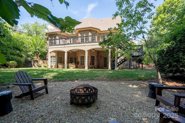 rear view of house with a yard, a balcony, a patio, and an outdoor fire pit