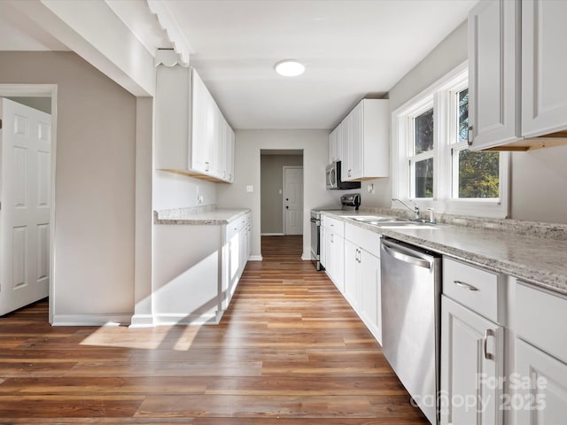 kitchen featuring sink, white cabinets, stainless steel appliances, and light hardwood / wood-style flooring