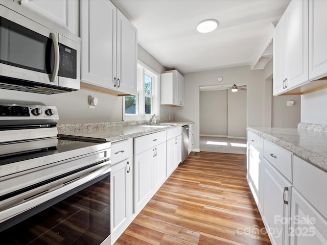 kitchen with light stone counters, sink, white cabinets, and stainless steel appliances