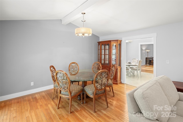 dining area featuring lofted ceiling with beams, a chandelier, and light hardwood / wood-style floors