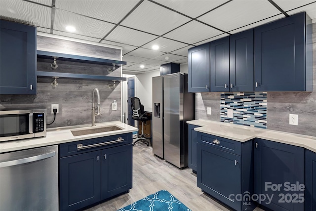 kitchen featuring blue cabinets, appliances with stainless steel finishes, sink, and light wood-type flooring