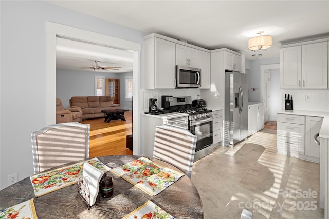 kitchen featuring stainless steel appliances, white cabinetry, ceiling fan, and decorative backsplash