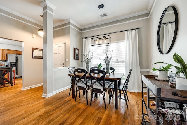 dining space with crown molding, light hardwood / wood-style flooring, and decorative columns