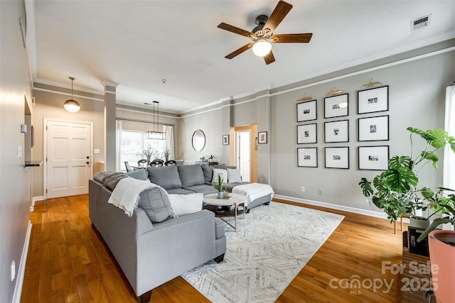 living room with ceiling fan, ornamental molding, and wood-type flooring