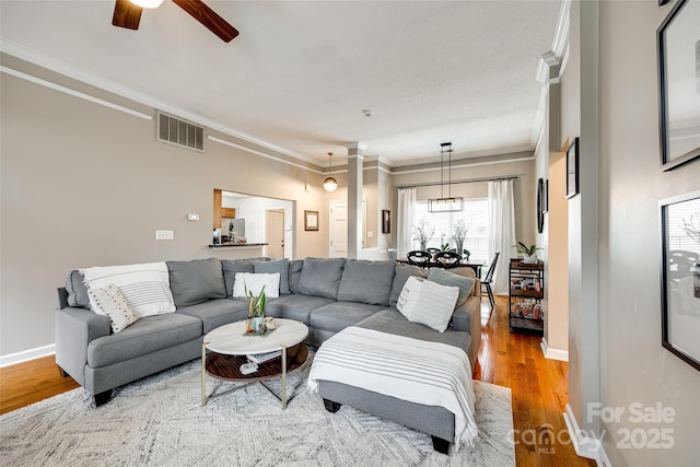 living room with ceiling fan, ornamental molding, hardwood / wood-style floors, and decorative columns