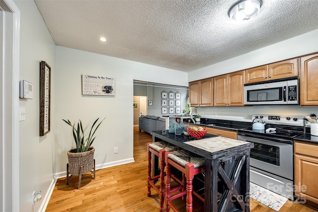 kitchen with stainless steel appliances, light hardwood / wood-style flooring, and a textured ceiling