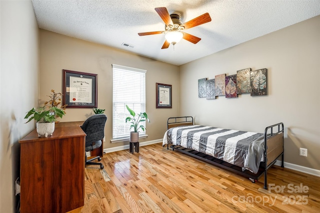 bedroom with a textured ceiling, ceiling fan, and light wood-type flooring