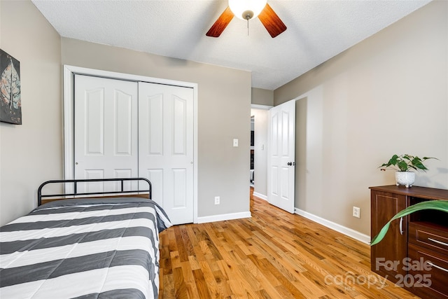 bedroom featuring light hardwood / wood-style floors, a textured ceiling, ceiling fan, and a closet