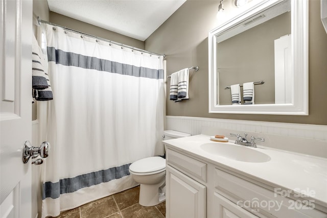 bathroom featuring vanity, a textured ceiling, toilet, and walk in shower