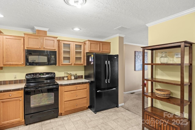 kitchen with ornamental molding, tile counters, black appliances, and a textured ceiling