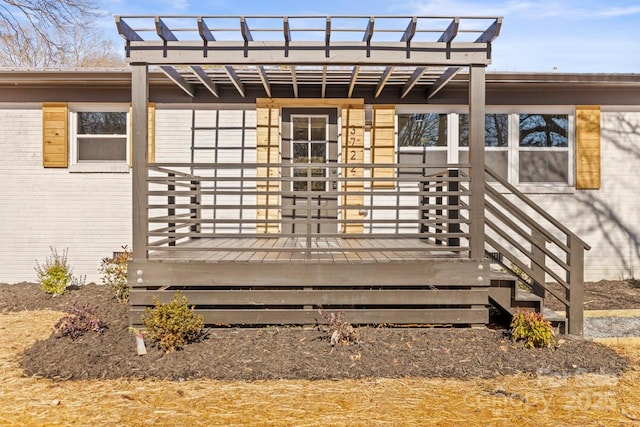 view of exterior entry with a wooden deck and a pergola