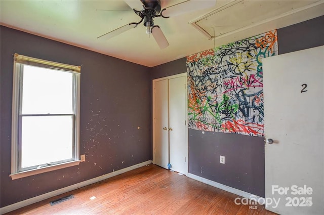 empty room with hardwood / wood-style floors, ceiling fan, and a wealth of natural light