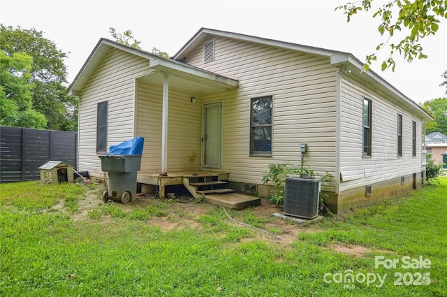 back of property with central AC and a yard