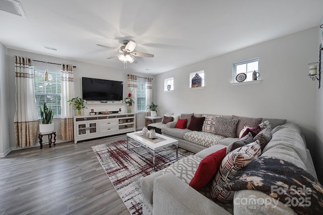 living area with visible vents, a ceiling fan, and wood finished floors
