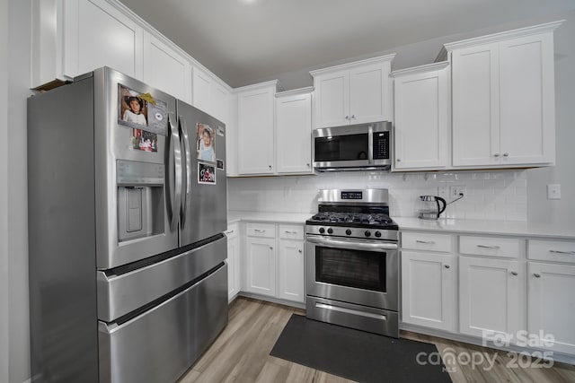 kitchen featuring light countertops, stainless steel appliances, white cabinetry, and light wood-type flooring