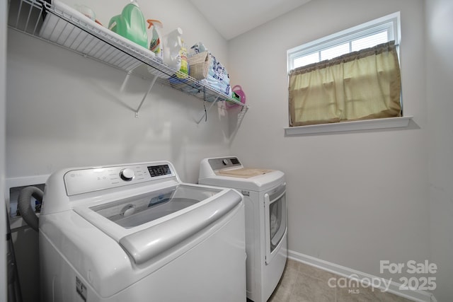 clothes washing area featuring washer and dryer, light tile patterned flooring, laundry area, and baseboards