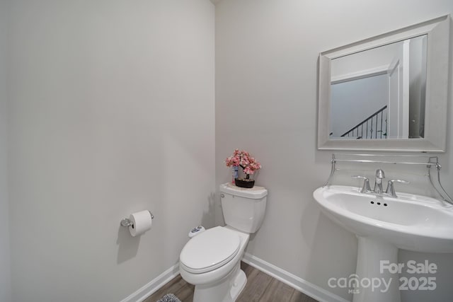 bathroom featuring a sink, baseboards, toilet, and wood finished floors