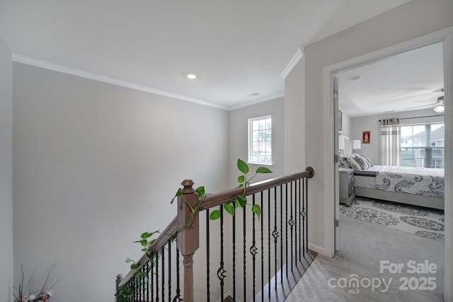 hall featuring visible vents, crown molding, baseboards, an upstairs landing, and carpet flooring