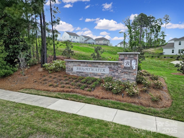 community sign featuring a yard and a residential view
