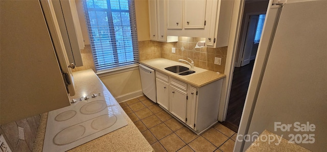 kitchen with white cabinetry, sink, backsplash, light tile patterned floors, and white appliances