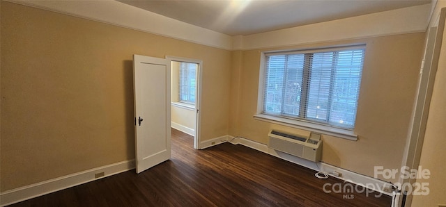 spare room featuring an AC wall unit and dark hardwood / wood-style floors