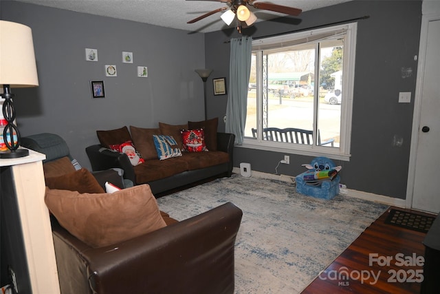 living room featuring a textured ceiling, ceiling fan, and dark wood-type flooring